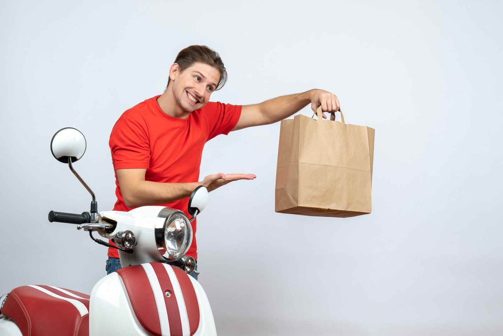 smiling-delivery-man-red-uniform-standing-near-scooter-pointing-paper-box-white-background-11zon