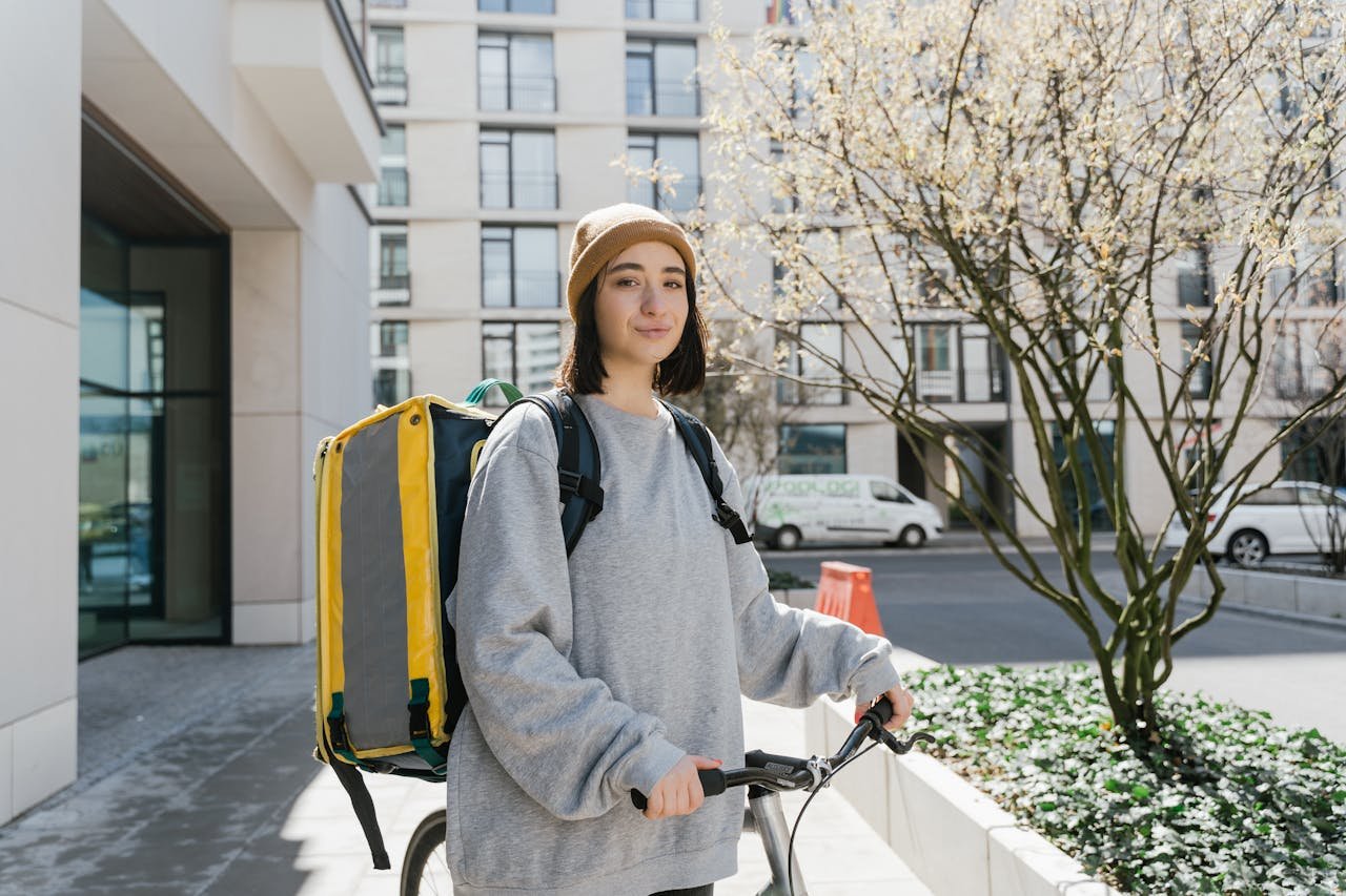Young woman cyclist with a delivery backpack on a city street ready for food delivery.